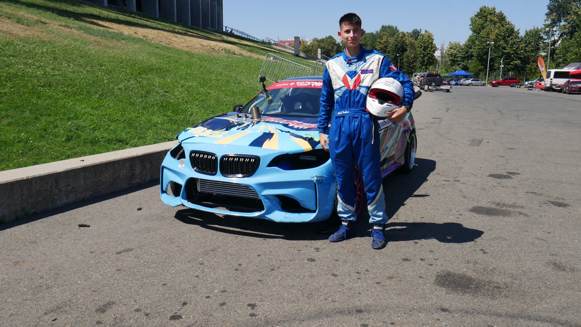 Pilotul Toro Drift cu casca în mână lângă mașina de competiție